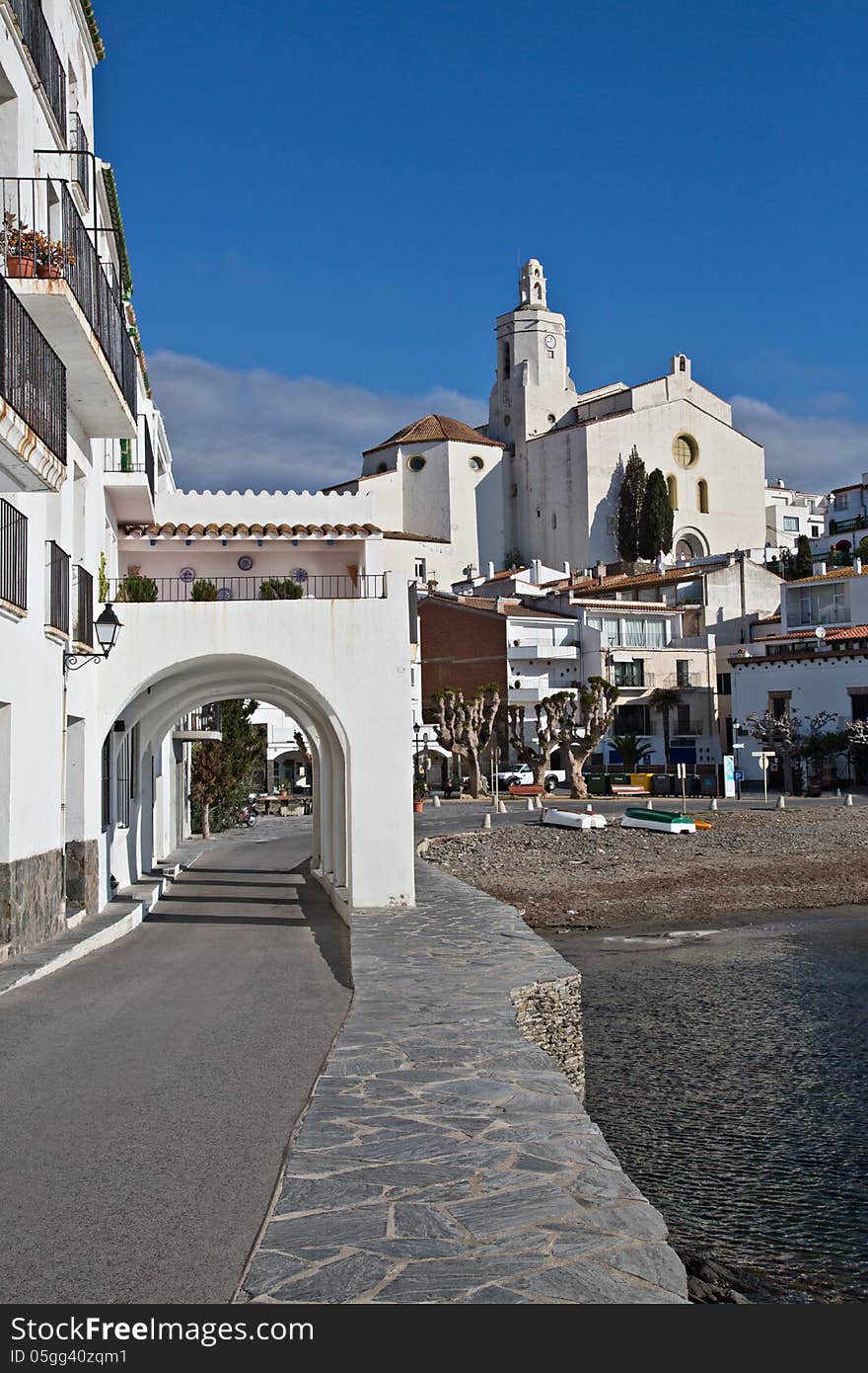 Clear blue sky day in Cadaques, Spain with Church of Santa Maria in the background and famous arches in foreground. Clear blue sky day in Cadaques, Spain with Church of Santa Maria in the background and famous arches in foreground