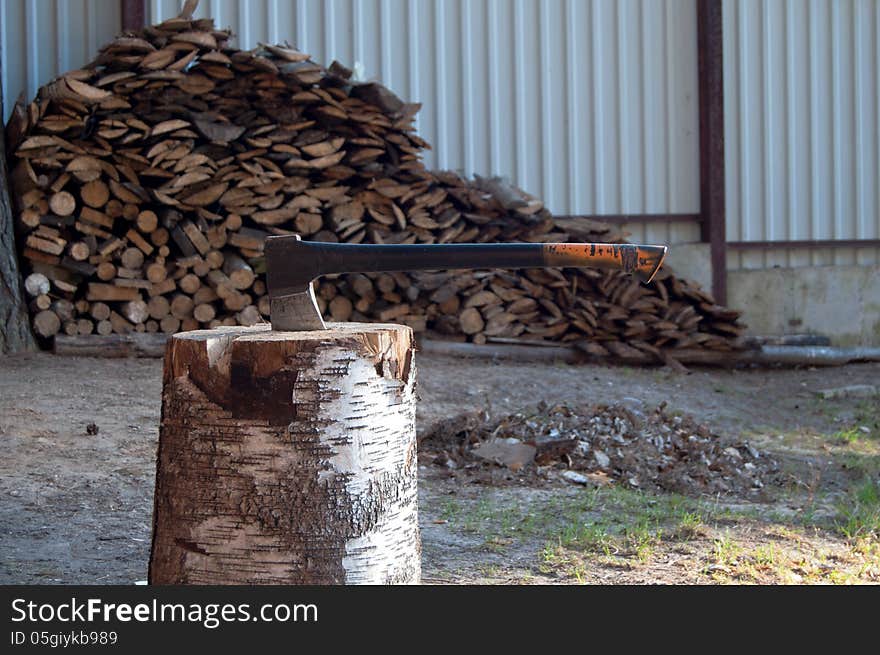 Axe in stump on the background of firewood. Axe in stump on the background of firewood