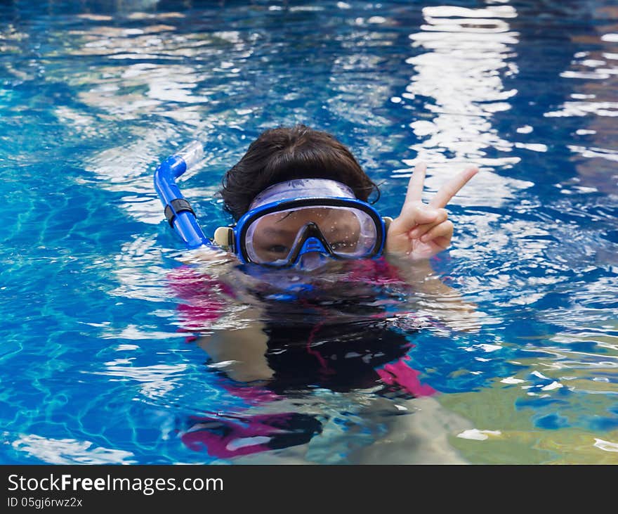 Girl relaxing on the side of a swimming pool wearing goggles and snorkel. Girl relaxing on the side of a swimming pool wearing goggles and snorkel