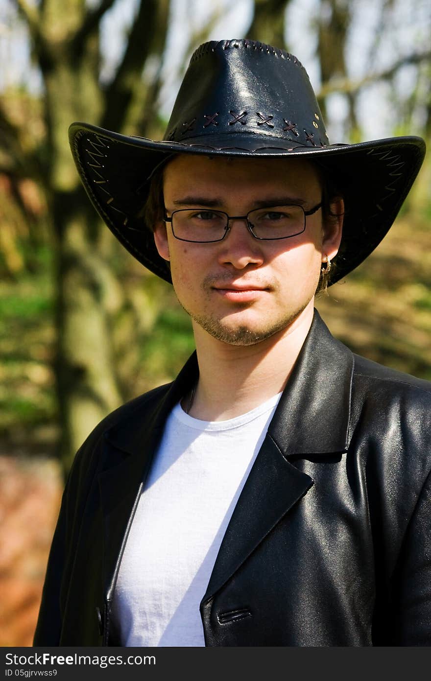 Young attractive man in a black leather coat and hat