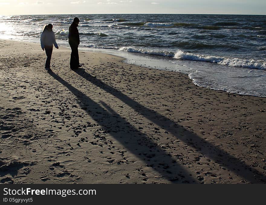 Two silhouettes of people on the beach on sunset