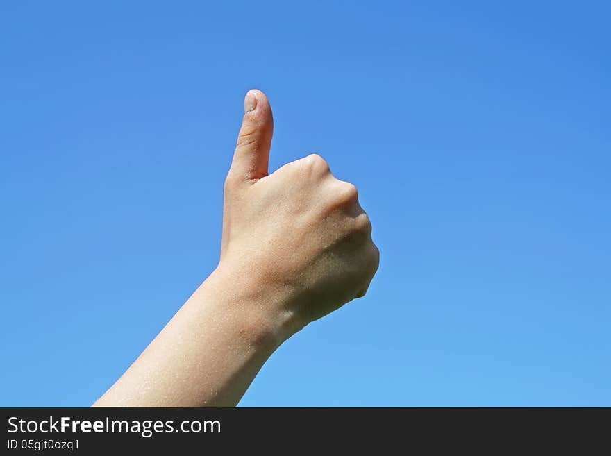 A close-up of a sign of thumb up on a blue sky background. A close-up of a sign of thumb up on a blue sky background.