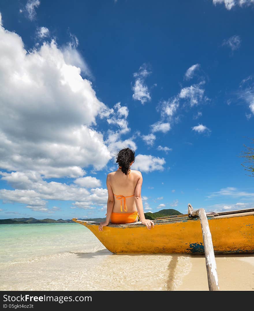 Young girl sit on boat on white beach