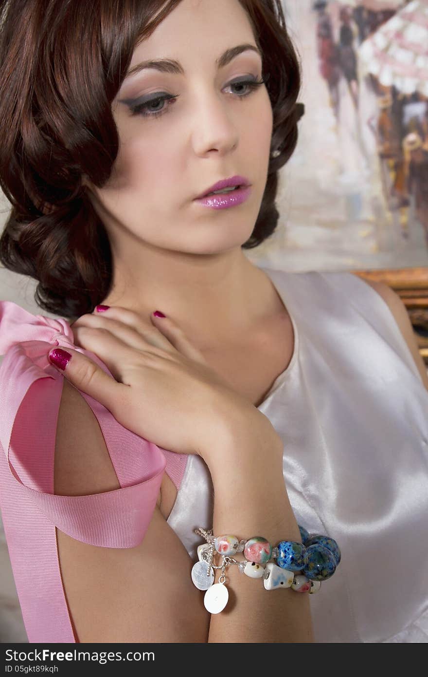 Young attractive woman wearing a necklace, bracelet and a satin bridal designer gown. Young attractive woman wearing a necklace, bracelet and a satin bridal designer gown