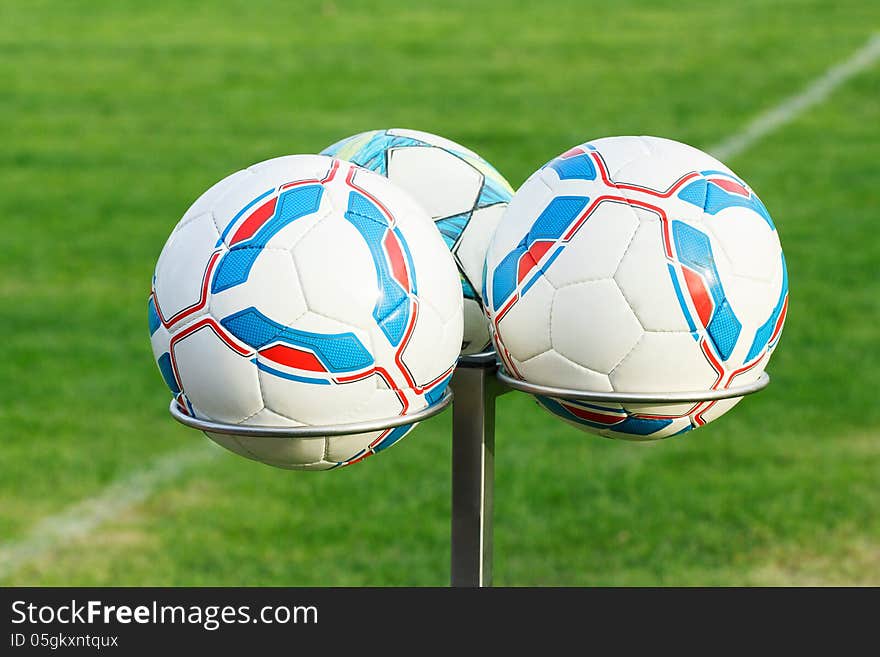 Three football bals on holders with green grass in background