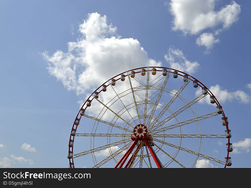 Ferris wheel on the background of sky with clouds