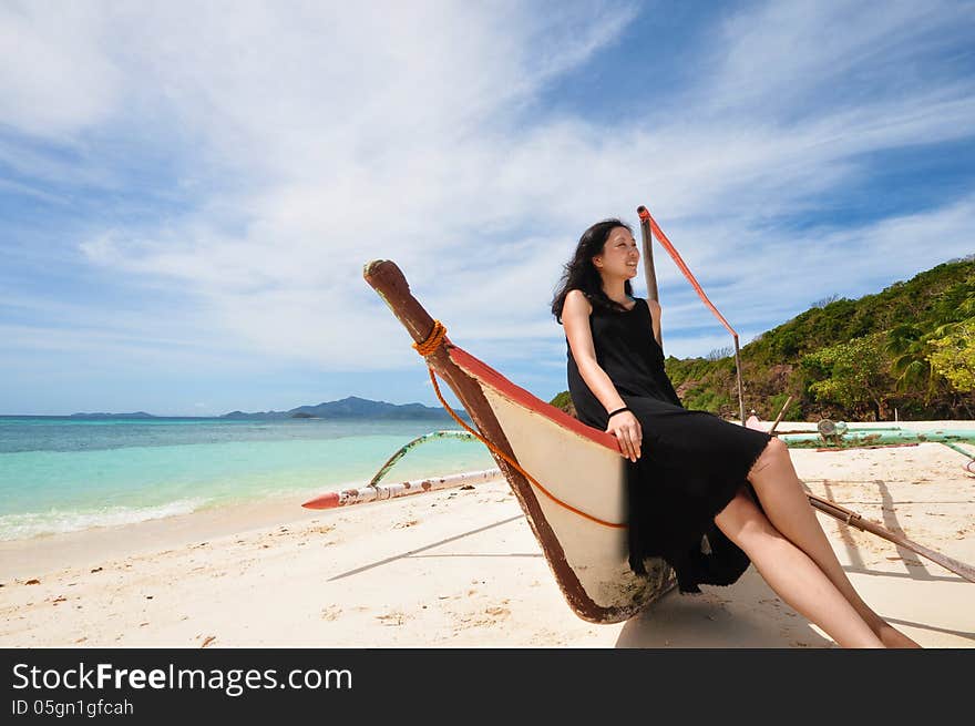 Happy young girl sit on boat on white beach