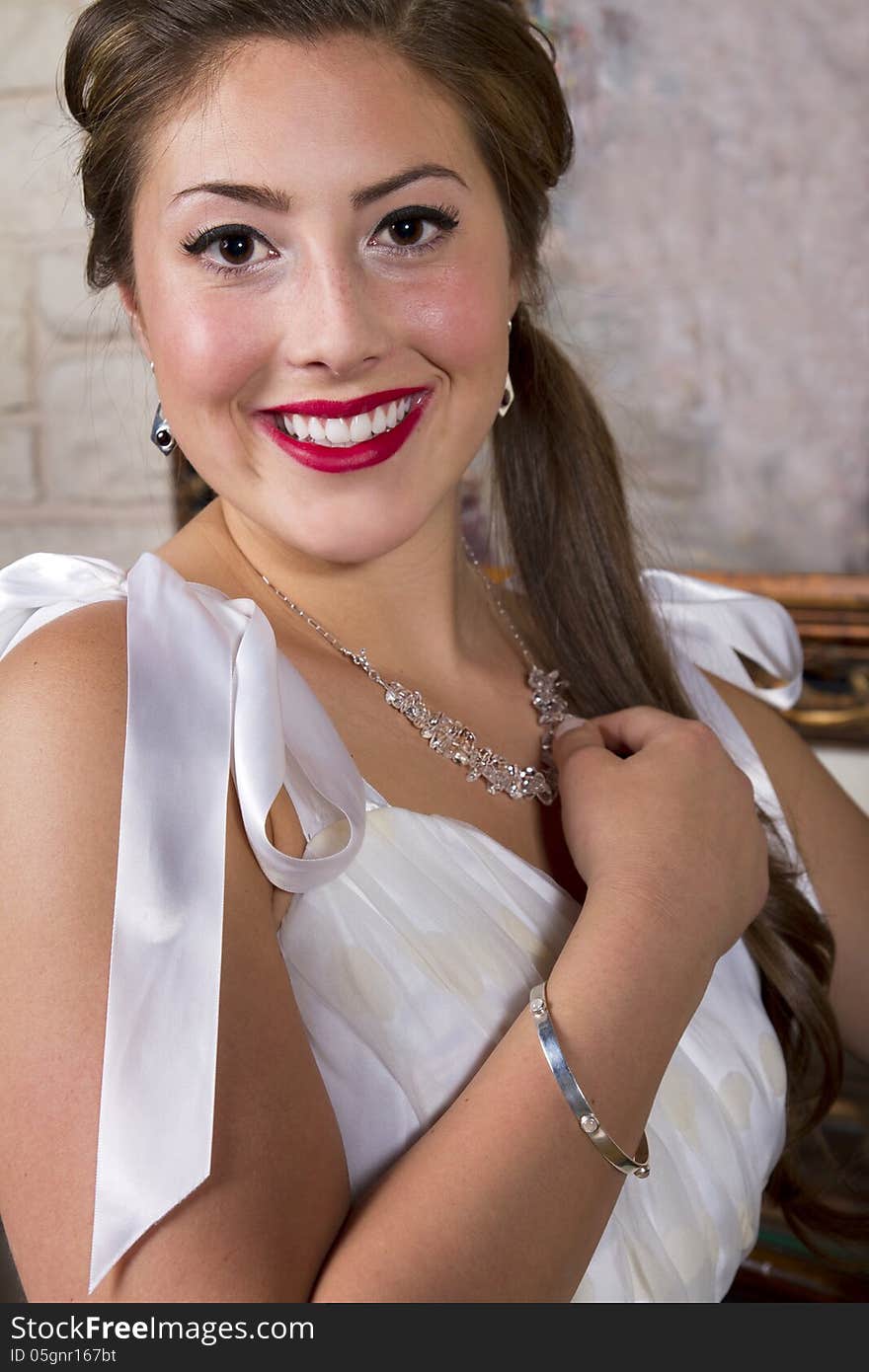 Young attractive woman wearing a necklace, bracelet and a satin bridal designer gown. Young attractive woman wearing a necklace, bracelet and a satin bridal designer gown