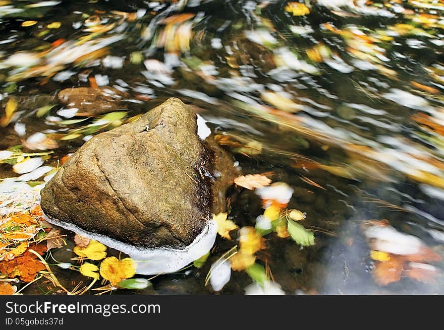 Lone stone in the creek generated by moving leaves. Lone stone in the creek generated by moving leaves