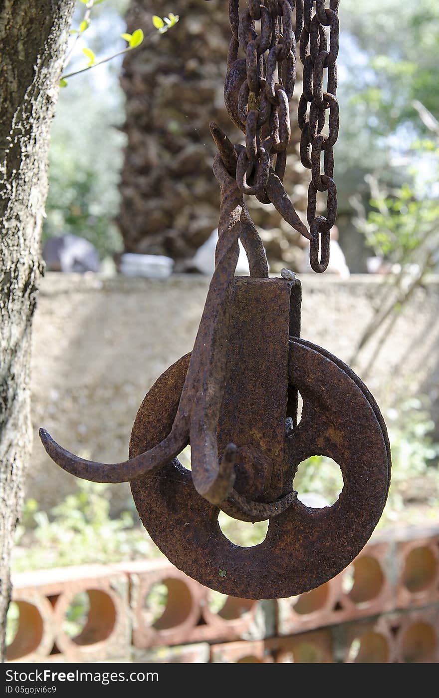 Old rusty pulley of the well, hanging with the chain. Old rusty pulley of the well, hanging with the chain.