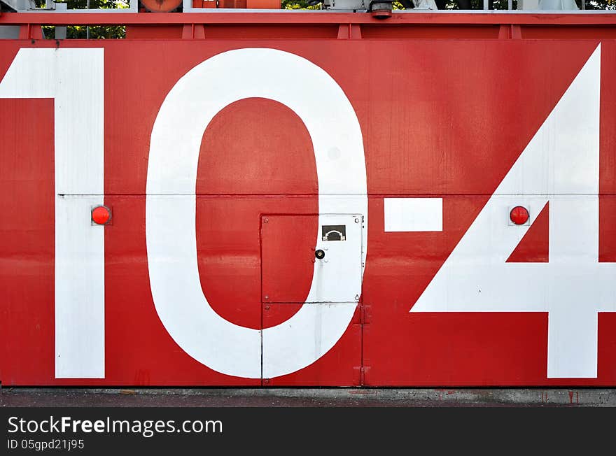 A red japanese tsunami watertight door in osaka bay area with the number 10-4 painted on it. A red japanese tsunami watertight door in osaka bay area with the number 10-4 painted on it