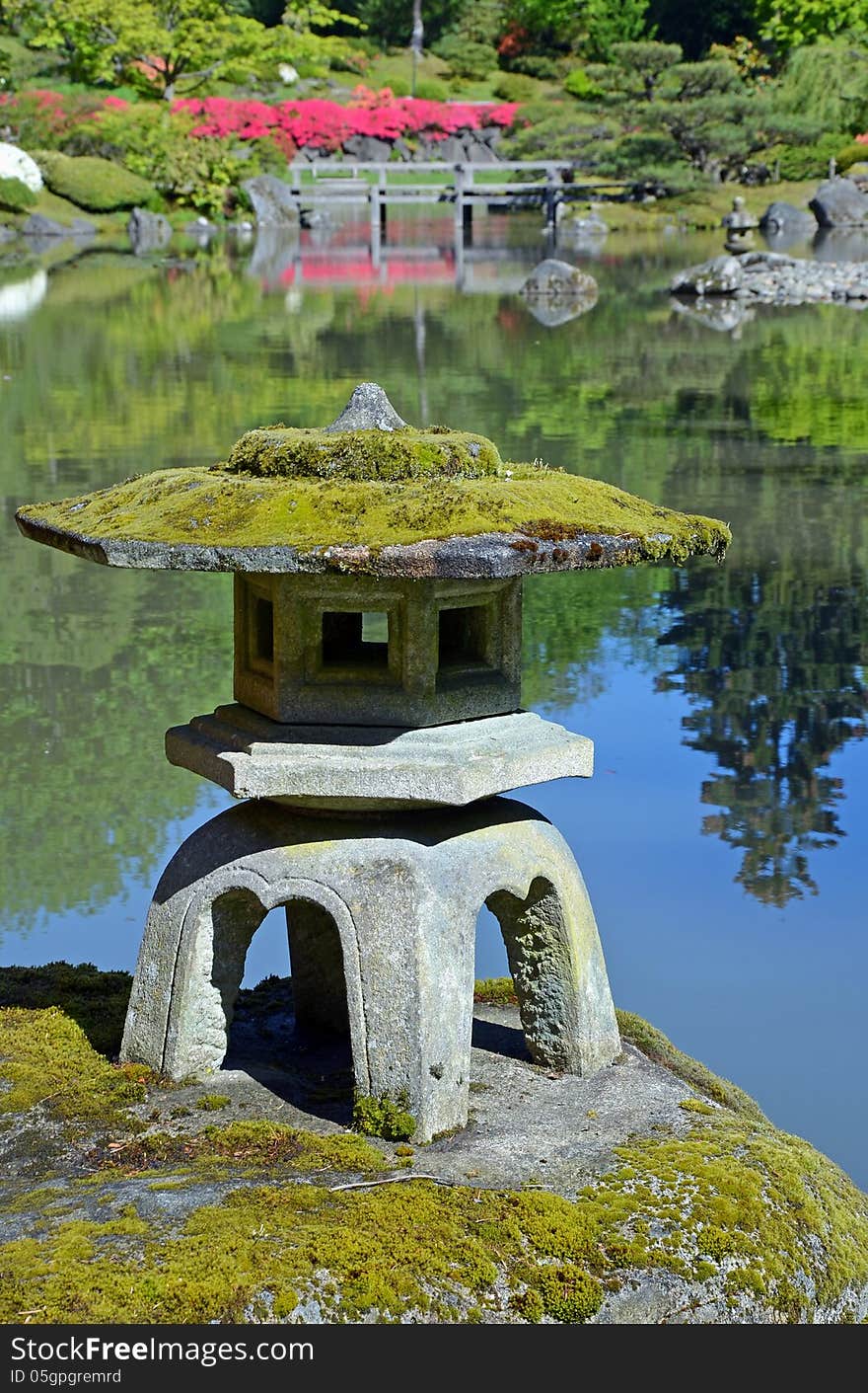 Rock lantern on rock in reflective pond in japanese botanical garden. Rock lantern on rock in reflective pond in japanese botanical garden