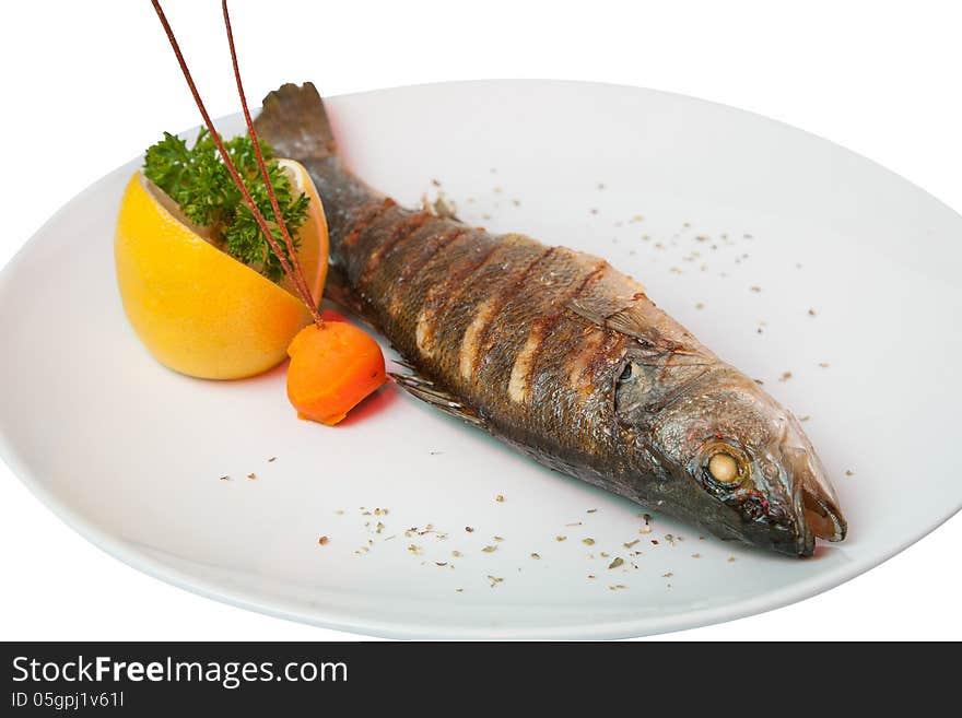 Fried fish decorated with lemon, carrots and vegetables