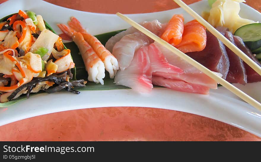 Sashimi and a squid salad served in a white plate. Sashimi and a squid salad served in a white plate