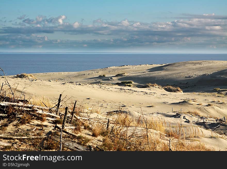 Sand dune at the beach with cloudy sky on summer day