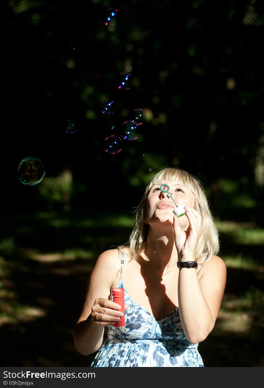 Young pregnant woman blowing soap bubbles outdoor