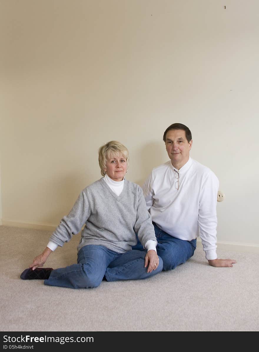 Middle aged couple sitting on the floor of the house they raised their children in, just before moving out. Middle aged couple sitting on the floor of the house they raised their children in, just before moving out.