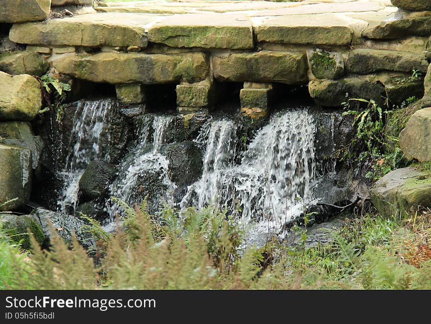 A Pleasant Waterfall Running Under a Stone Paved Path. A Pleasant Waterfall Running Under a Stone Paved Path.