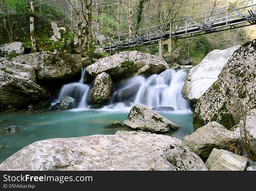 Bridge over the rapid flow of a mountain stream. Bridge over the rapid flow of a mountain stream