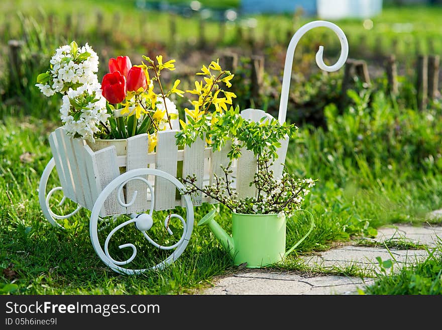 Decorative wheelbarrow and watering can with bright flowers. Decorative wheelbarrow and watering can with bright flowers