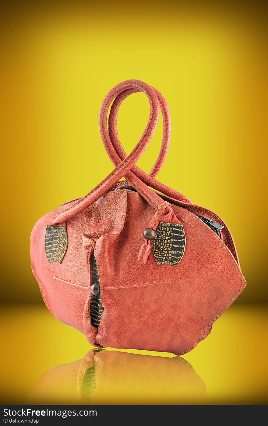 Female elegant leather handbag photographed against a yellow background. Female elegant leather handbag photographed against a yellow background