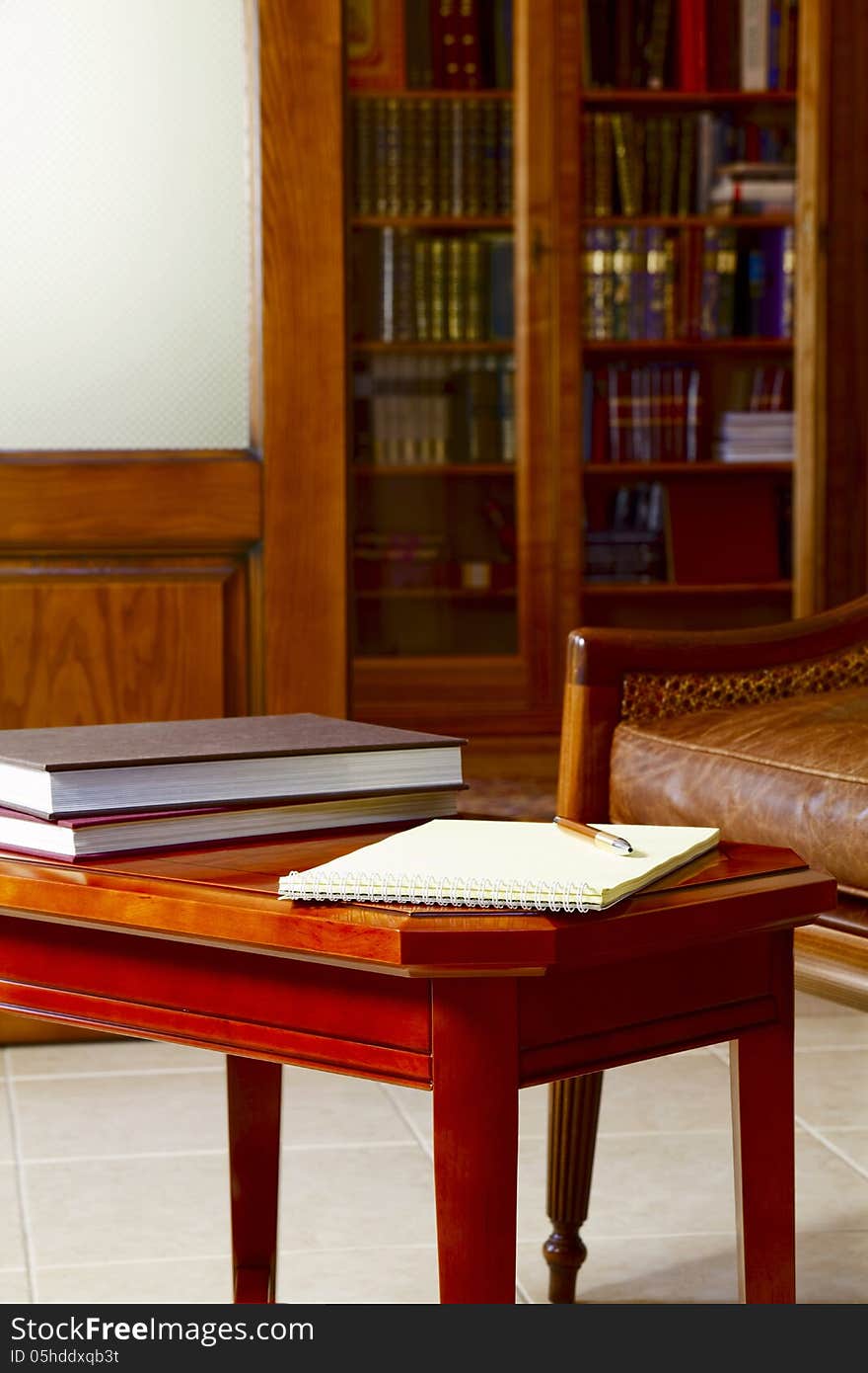 Coffee table with notebook and books on the background of the bookcase. Coffee table with notebook and books on the background of the bookcase