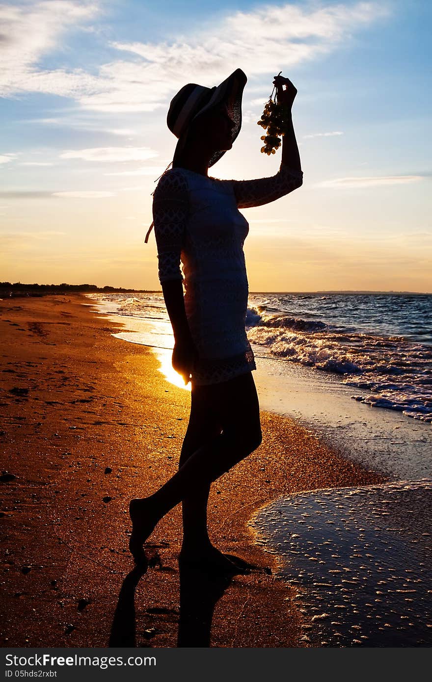 Beautiful young woman in hat atsea shore holding grapes. Beautiful young woman in hat atsea shore holding grapes