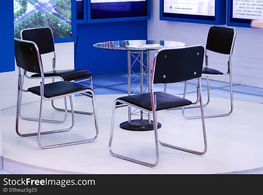 four black chairs are around a round glass table before meeting start. four black chairs are around a round glass table before meeting start