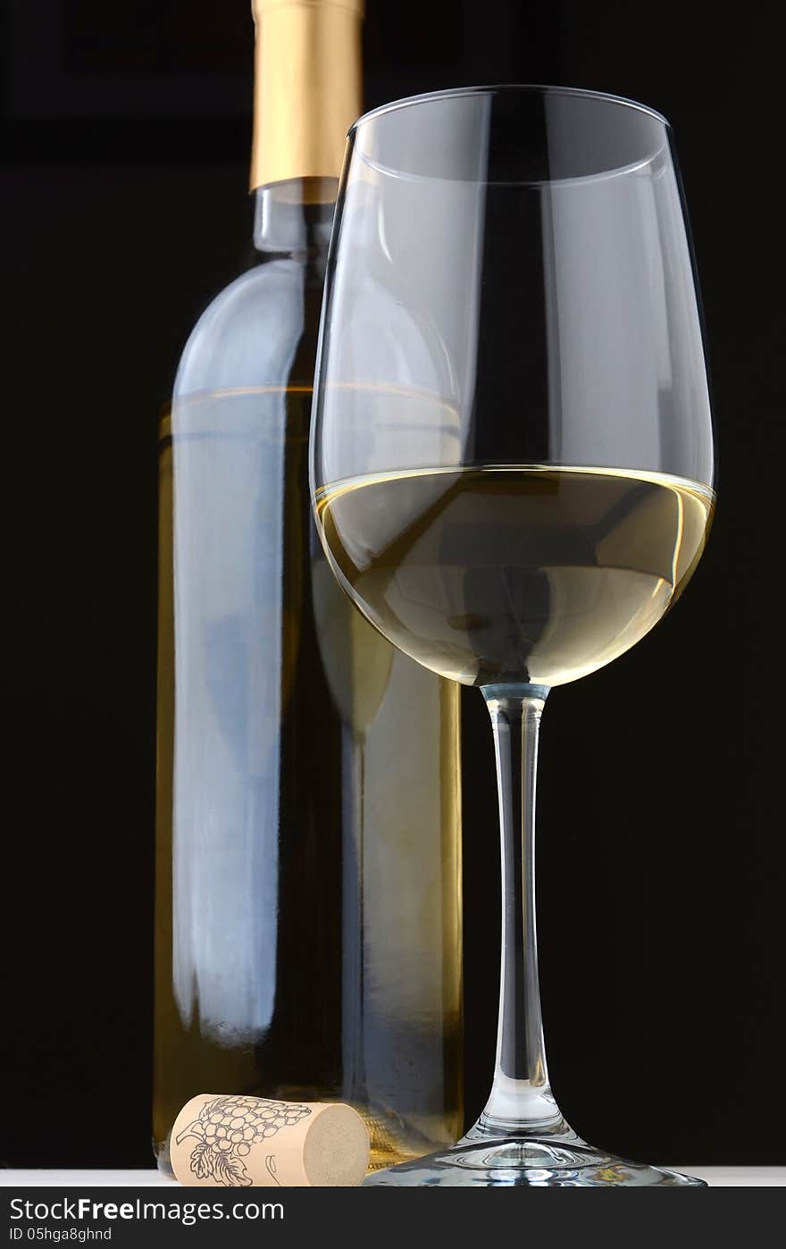 A glass of white wine with wine bottle and cork on a black background. A glass of white wine with wine bottle and cork on a black background.