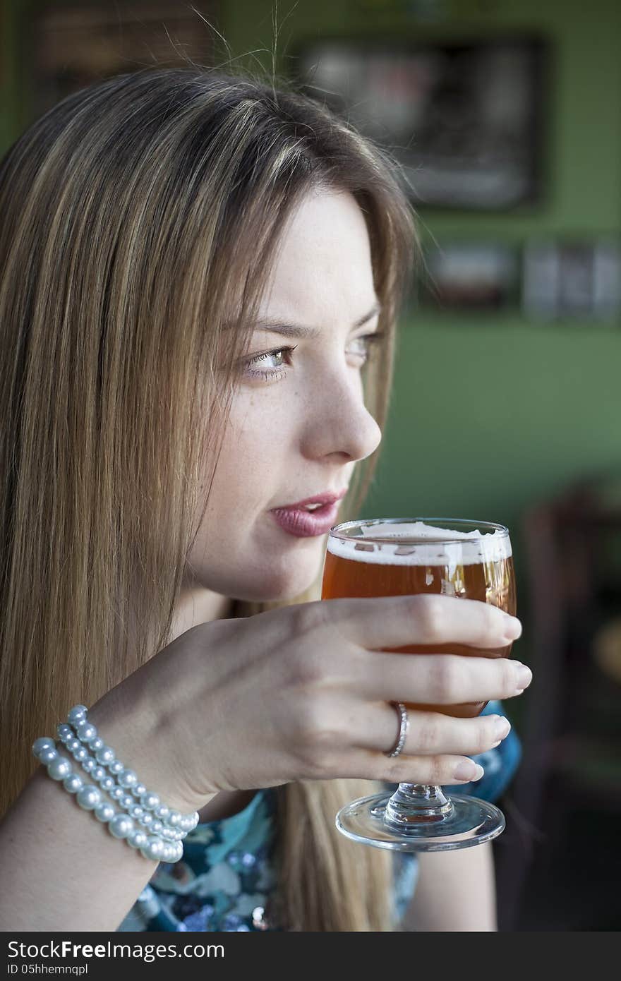 Blonde Woman with Beautiful Blue Eyes Drinks a Goblet of Beer