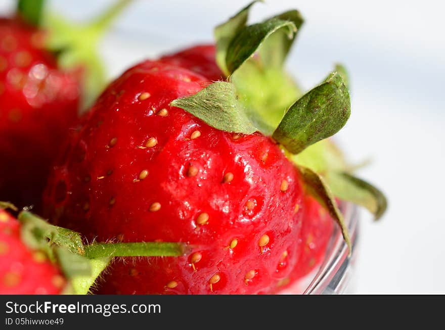 Macro shot of strawberries in glass bowl isolated on white, shallow depth of field