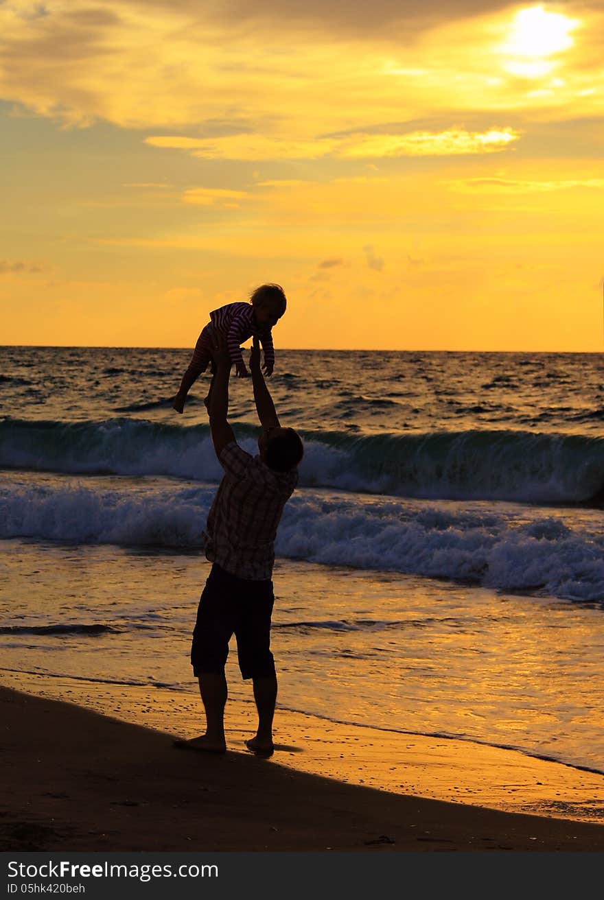 Father and daughter playing together on the beach at sunset