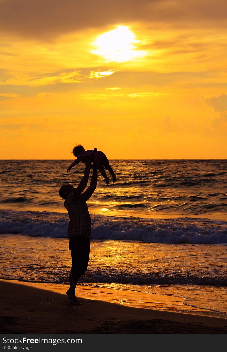 Father and daughter playing together on the beach at sunset