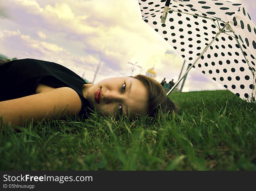 Beautiful girl on a green lawn with umbrella