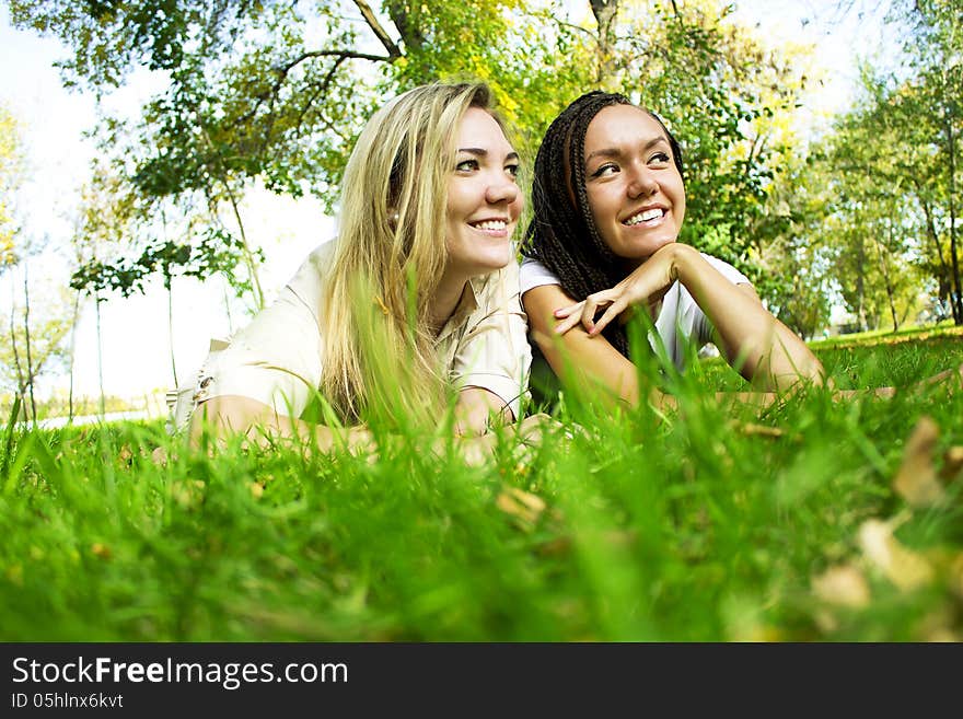 Two beautiful girls rest on a green glade. Two beautiful girls rest on a green glade