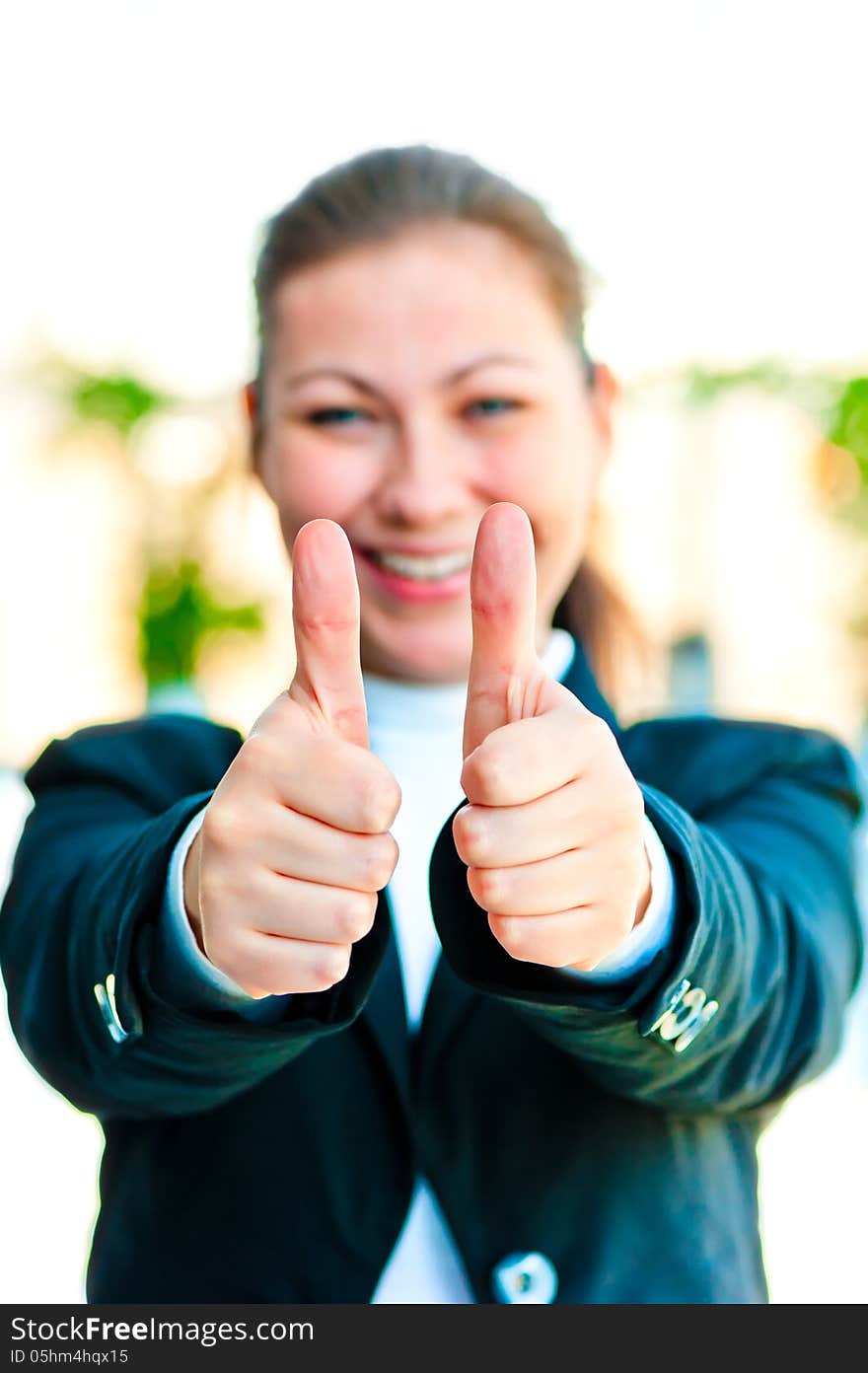 Young happy businesswoman shows that everything is fine on the background of office interior