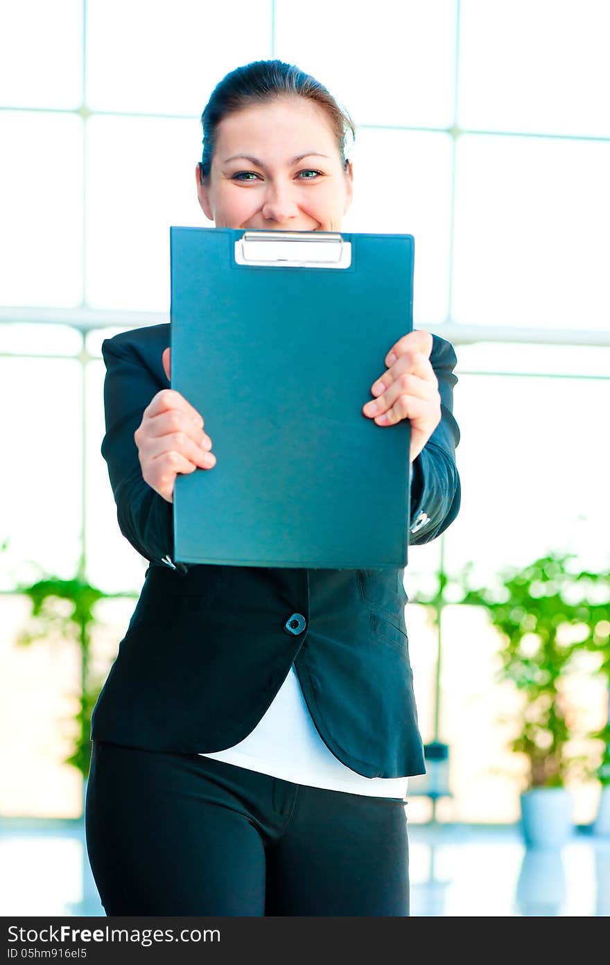 Smiling girl shows the empty office folder on office background