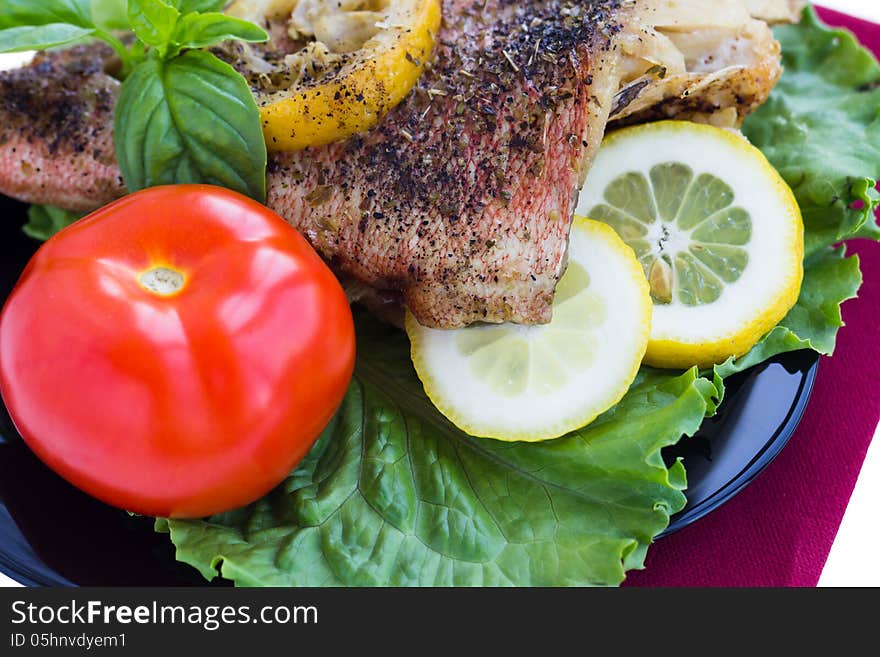 Baked grouper served with lemon and basil on black plate