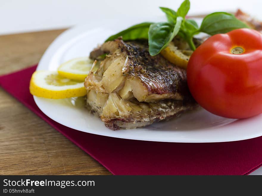 Served grilled fish with lemon and basil with tomato