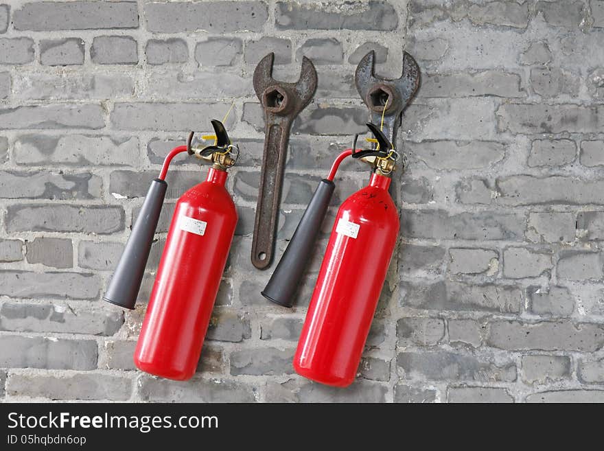 Fire extinguishers and spanners hanged on brick wall