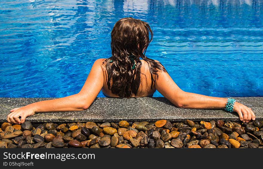 The young woman sits in the pool. The young woman sits in the pool