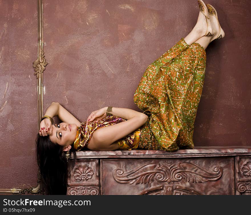 Portrait of beauty sensual young woman in oriental style in luxury room laying on fireplace