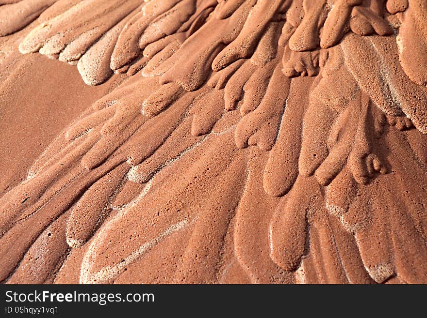 Wet red sand. Water has etched a pattern into sand. Wet red sand. Water has etched a pattern into sand