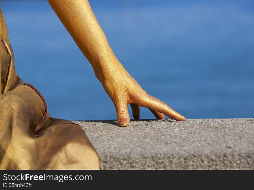 Woman's hand animator painted gold color on the seafront. Woman's hand animator painted gold color on the seafront