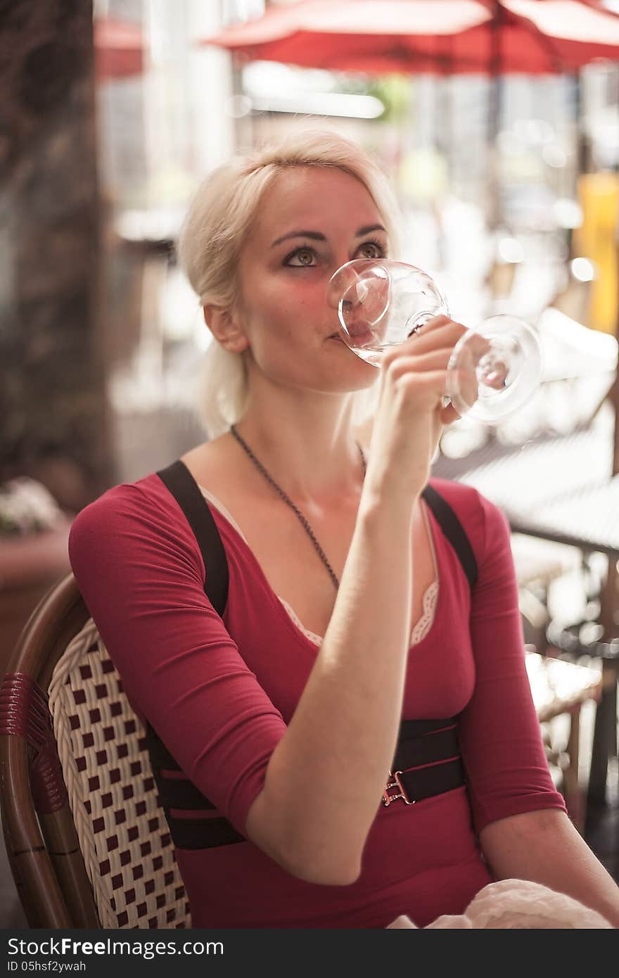 Portrait of a beautiful blond woman shot outdoors at a cafe. She has green eyes and bleached blond hair and is holding a glass of white wine. Portrait of a beautiful blond woman shot outdoors at a cafe. She has green eyes and bleached blond hair and is holding a glass of white wine.