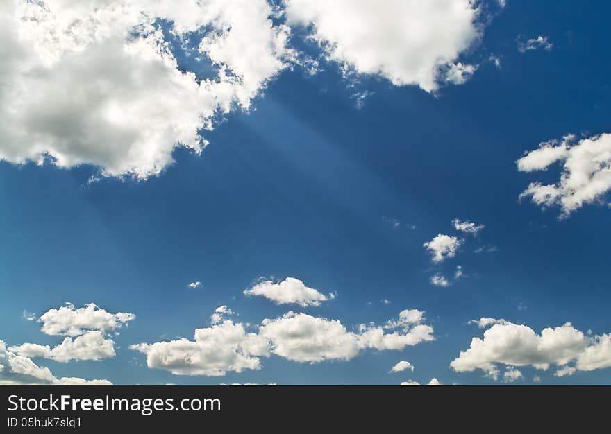 Bright blue cloudy sky with sunbeams from clouds