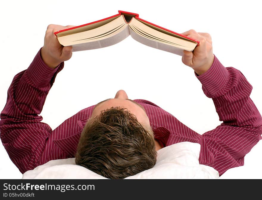 Young man lying down reading a book on bed. Young man lying down reading a book on bed.