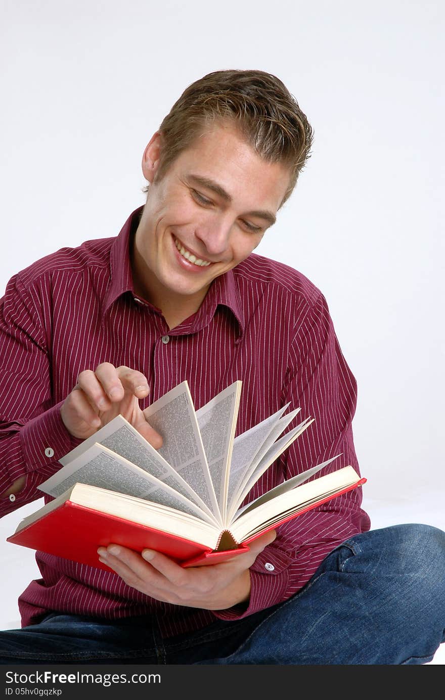 Happy young man holding and reading a red book. Happy young man holding and reading a red book.