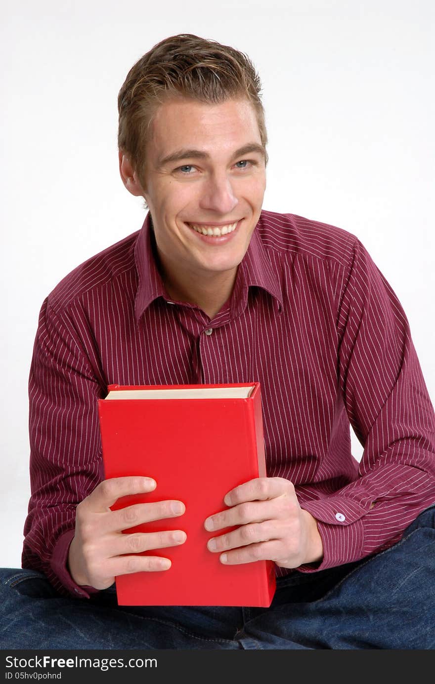 Happy young man holding and reading a red book. Happy young man holding and reading a red book.