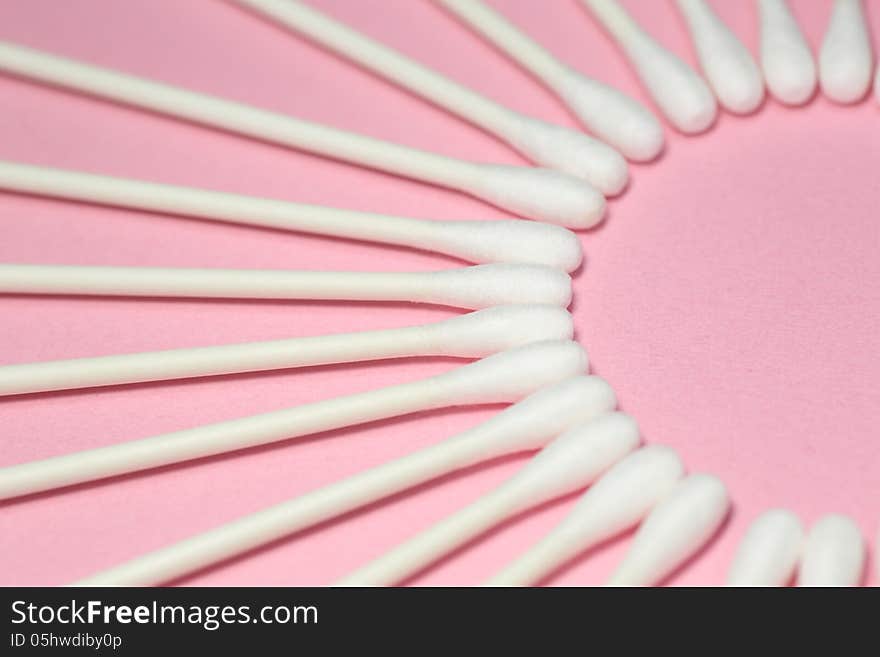 Cotton swabs which were displayed to draw a circle on a pink background